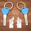 Two house keys with blue tops and matching metal keychains shaped like a broken house, lying on a wooden surface — symbolizing divided property ownership or a real estate dispute between co-owners. where a partition might make sense.